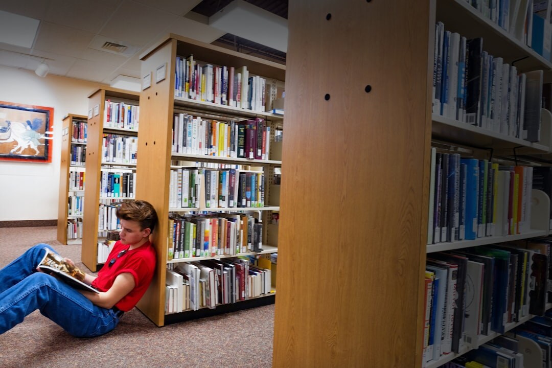 Student writing in notebook at library with books